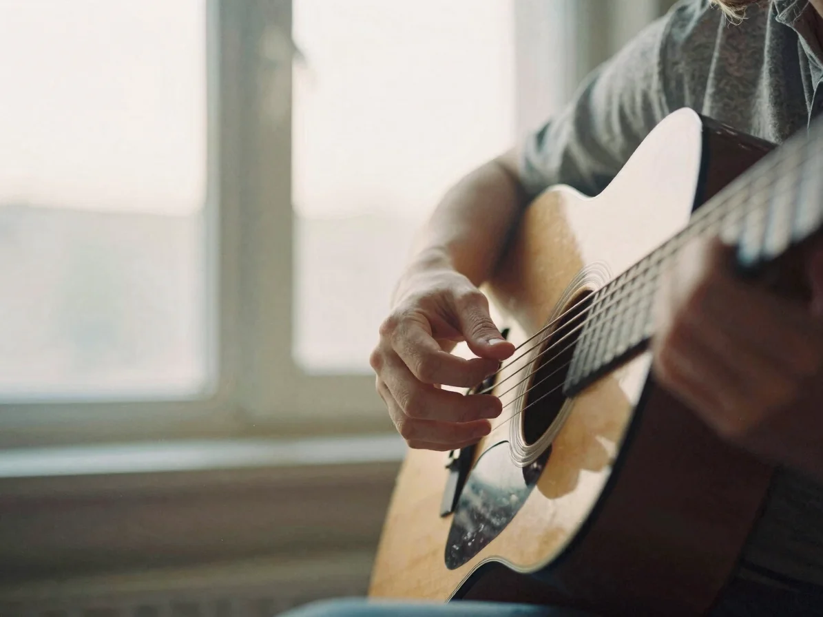 Warm editorial photograph of a person's hands on a guitar fretboa